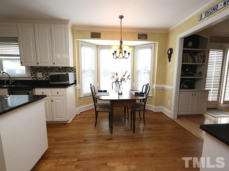 8208 Mourning Dove Road Raleigh, NC 27615 - Photo 11 of 25 a kitchen with stainless steel appliances granite countertop a stove top oven a sink a dining table and chairs with wooden floor