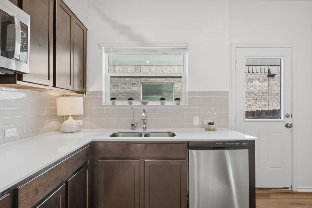 1233 Sweetspire Street Leander, TX 78641 - Photo 25 of 40 A well-appointed kitchen features dark wood cabinetry, white countertops, and stainless steel appliances.