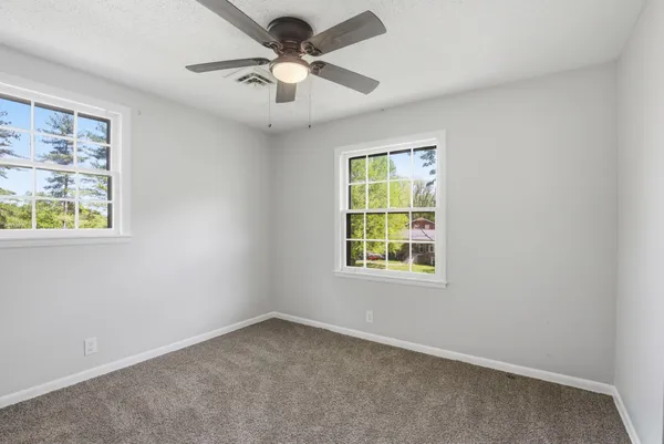 an empty room with a window and a fan