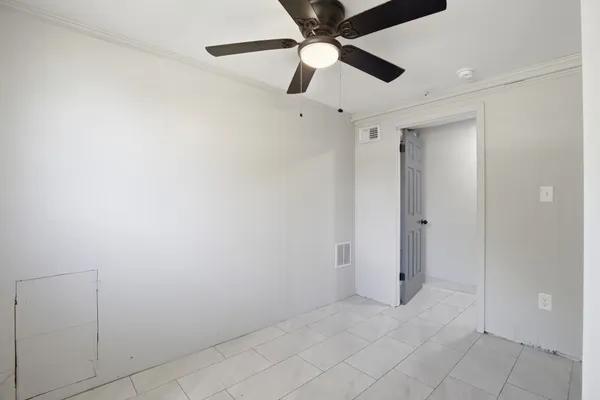 an empty room with closet and a chandelier fan