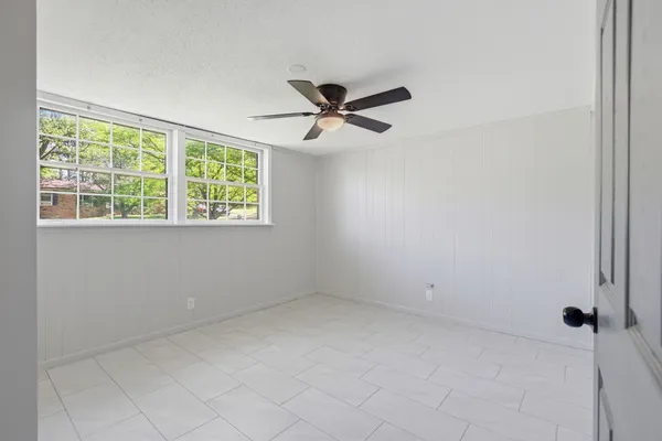 an empty room with a window and a fan