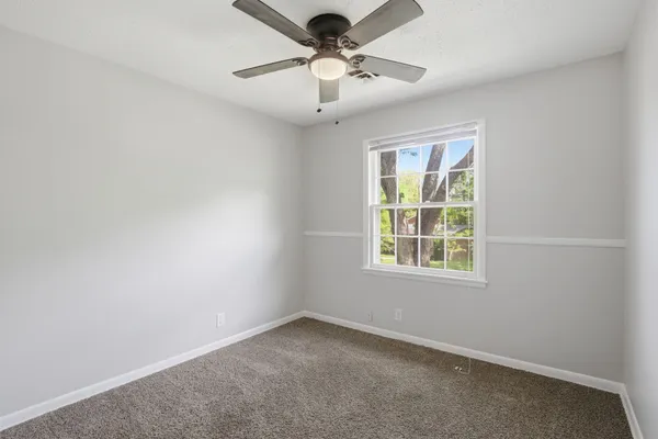 an empty room with a window and a fan