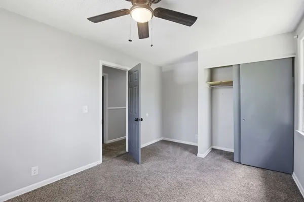 an empty room with a chandelier fan and a ceiling fan