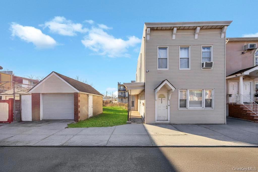 View of front of property featuring an outdoor structure, a detached garage, concrete driveway, and a front lawn
