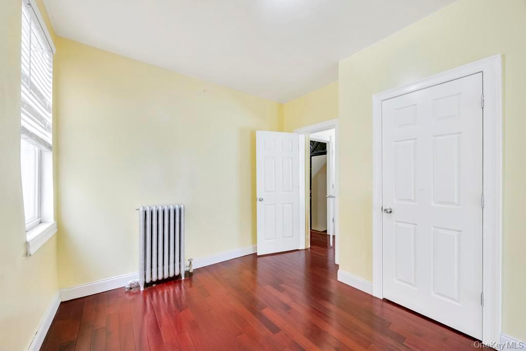 95-26 86th Street Queens, NY 11416 - Photo 21 of 28 Unfurnished bedroom featuring radiator heating unit and dark wood-style flooring