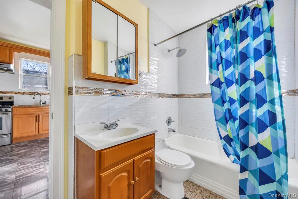 95-26 86th Street Queens, NY 11416 - Photo 23 of 28 Full bathroom featuring shower / bath combo, vanity, backsplash, and tile walls