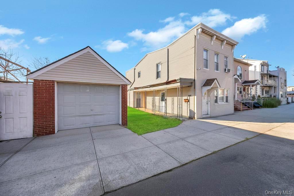 95-26 86th Street Queens, NY 11416 - Photo 4 of 28 View of front of home featuring driveway, a garage, an outbuilding, a front lawn, and brick siding