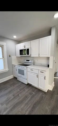 a kitchen with stainless steel appliances a white stove top oven cabinets and a window
