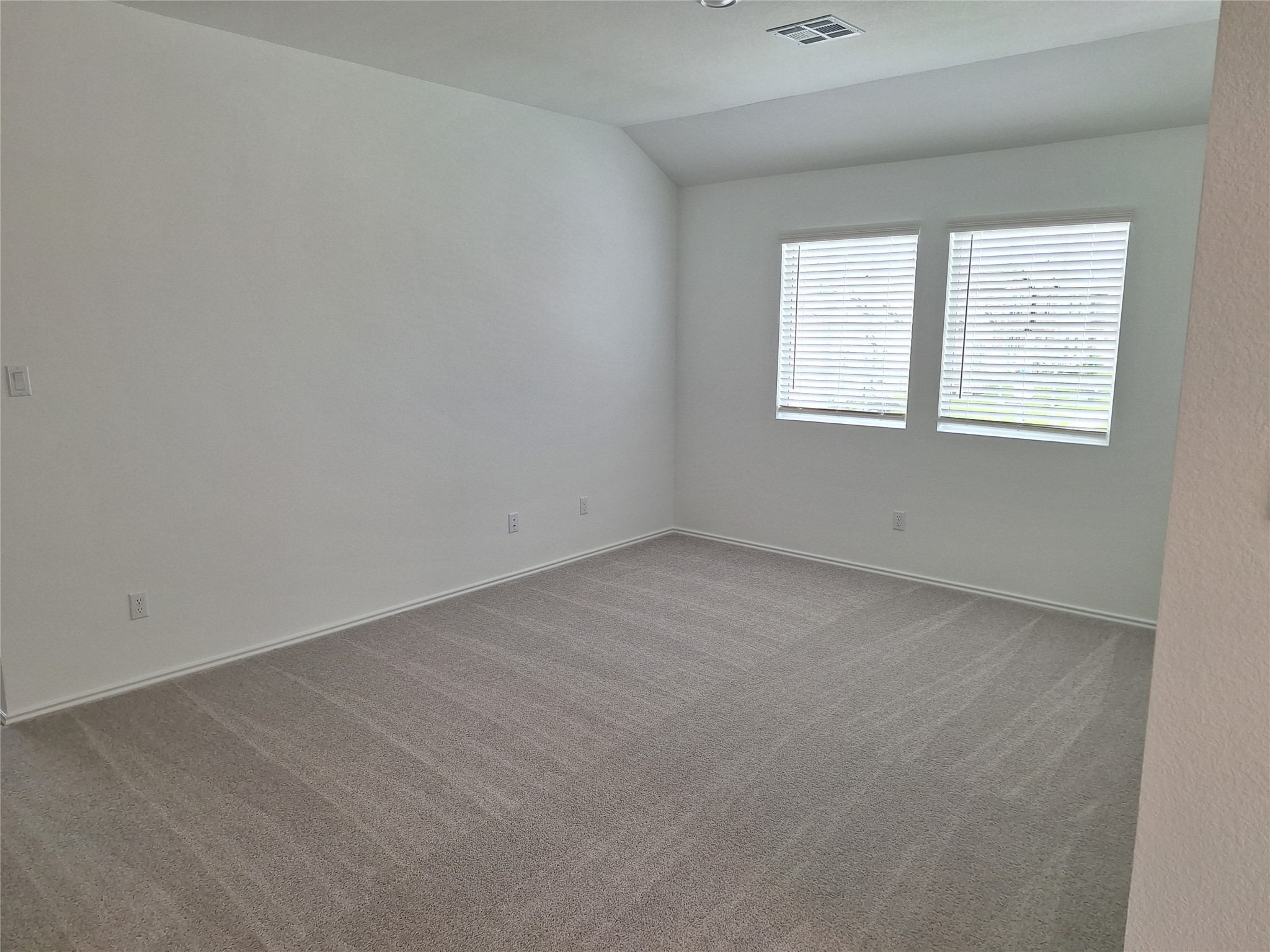 18001 Prairie Falcon Way Pflugerville, TX 78660 - Photo 7 of 38 Carpeted room featuring light neutral wall paint, two windows with horizontal blinds, and a flush-mount ceiling light fixture