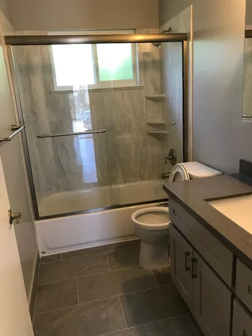 a bathroom with a granite countertop sink toilet and shower