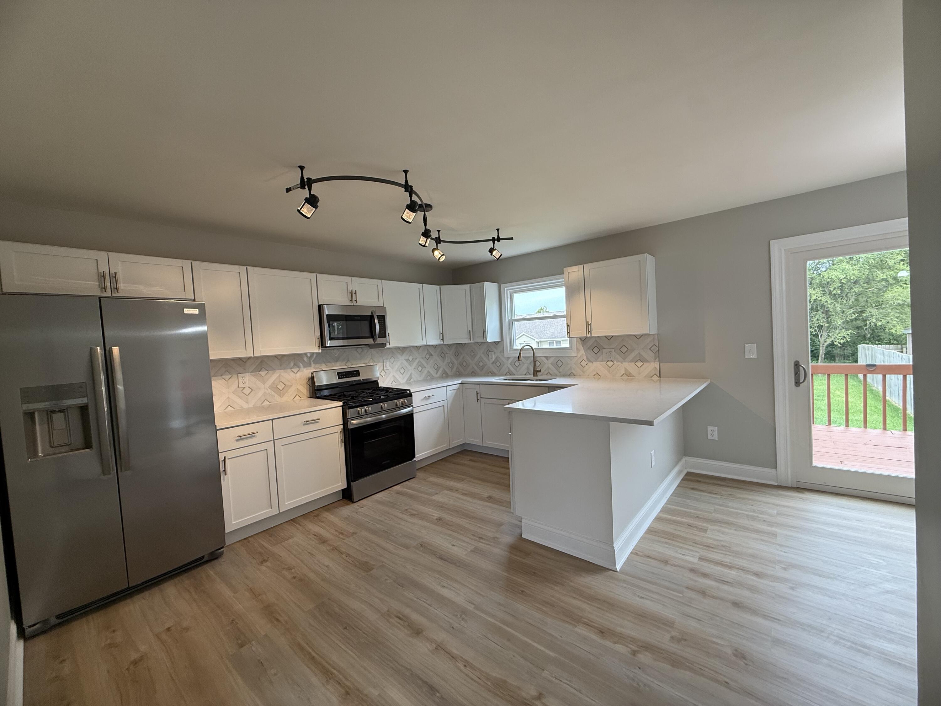 15895 Sherman Street Lowell, IN 46356 - Photo 10 of 36 a large kitchen with stainless steel appliances a large counter top a stove a refrigerator cabinets and a wooden floor