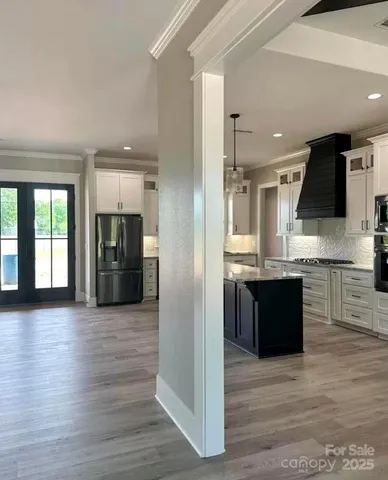 a large kitchen with a large counter top stainless steel appliances and wooden floor