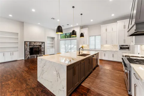 an empty room with wooden floor and kitchen view