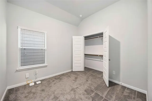 a view of an empty room with a window and cabinet