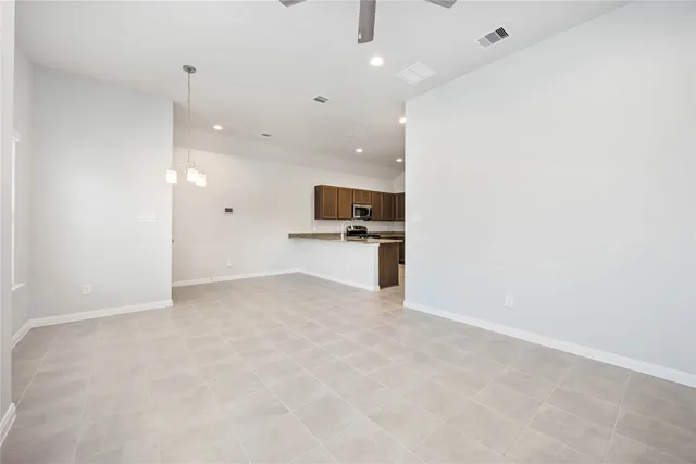 an empty room with kitchen and chandelier