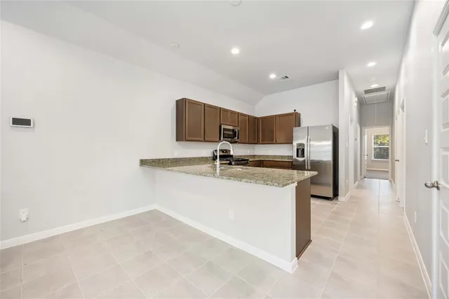 a kitchen with stainless steel appliances granite countertop a sink and a refrigerator