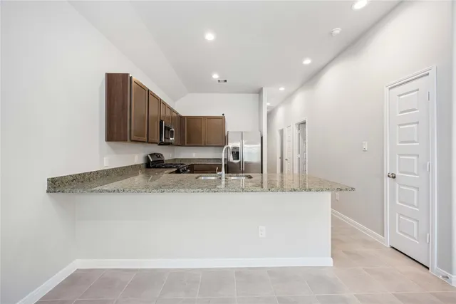 a kitchen with stainless steel appliances granite countertop a sink a stove and a refrigerator