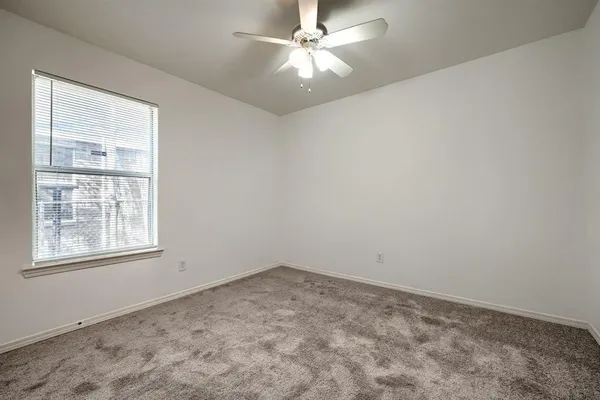 an empty room with a window and a fan