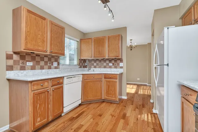 a kitchen with granite countertop a refrigerator a sink and wooden floors