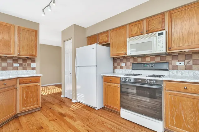 a kitchen with granite countertop a refrigerator stove and sink with wooden floor