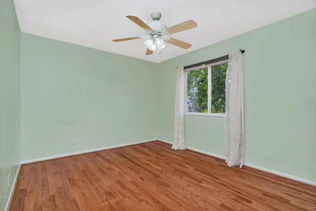 an empty room with wooden floor fan and windows