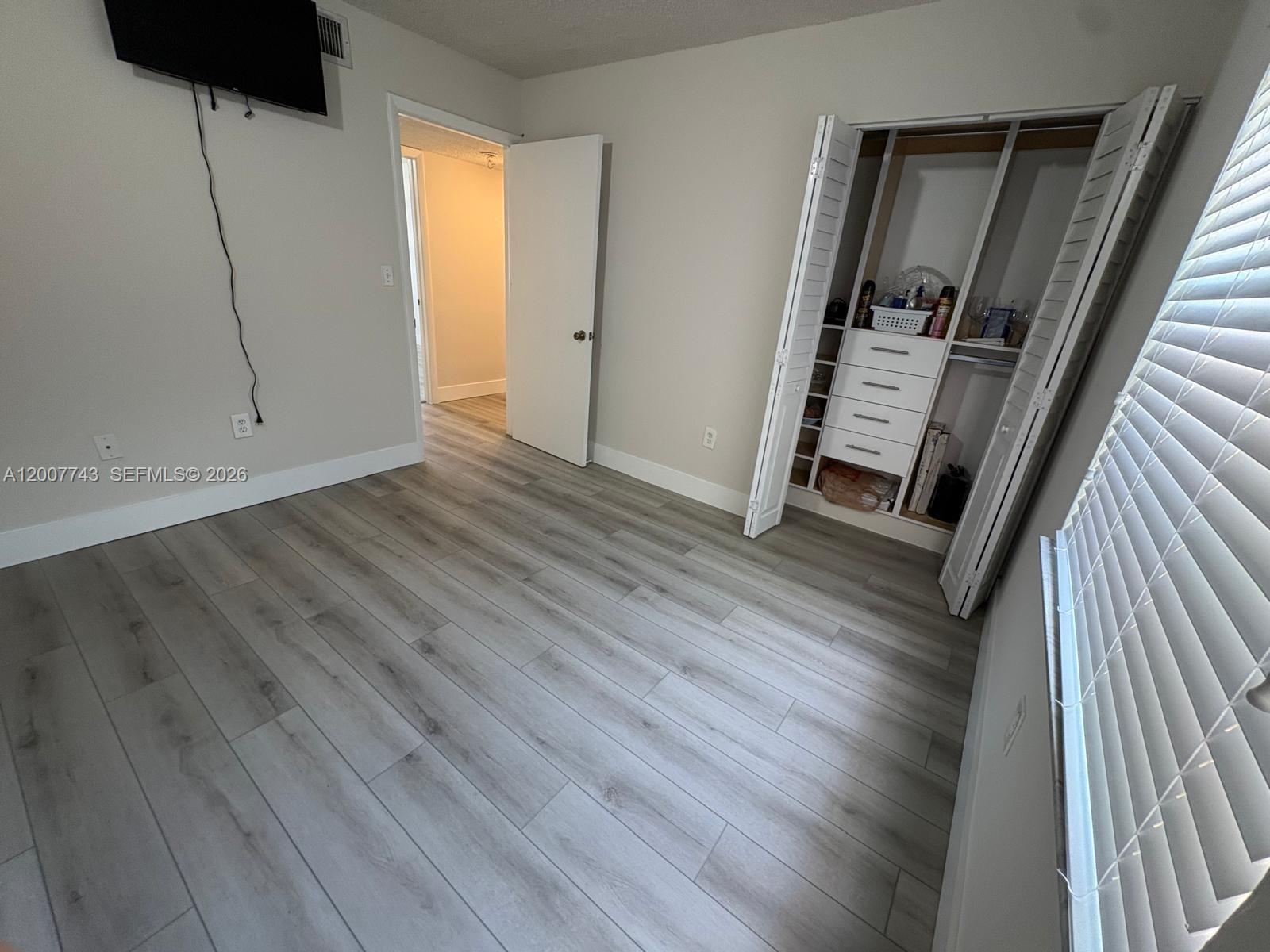 15250 Southwest 80th Street, Unit 4 Miami, FL 33193 - Photo 14 of 18 a view of an empty room with wooden floor and a window