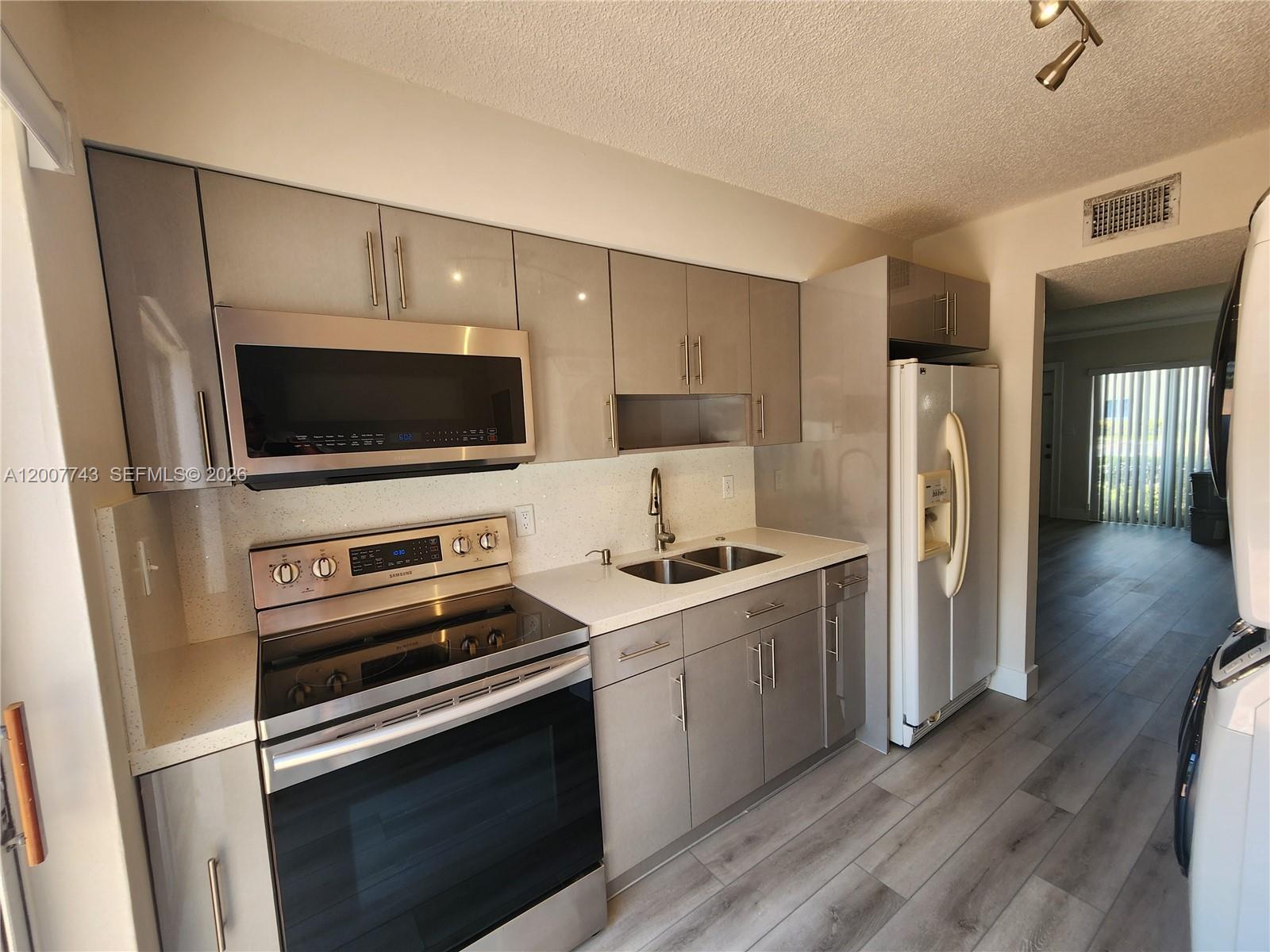 15250 Southwest 80th Street, Unit 4 Miami, FL 33193 - Photo 3 of 18 a kitchen with a refrigerator stove and wooden cabinets