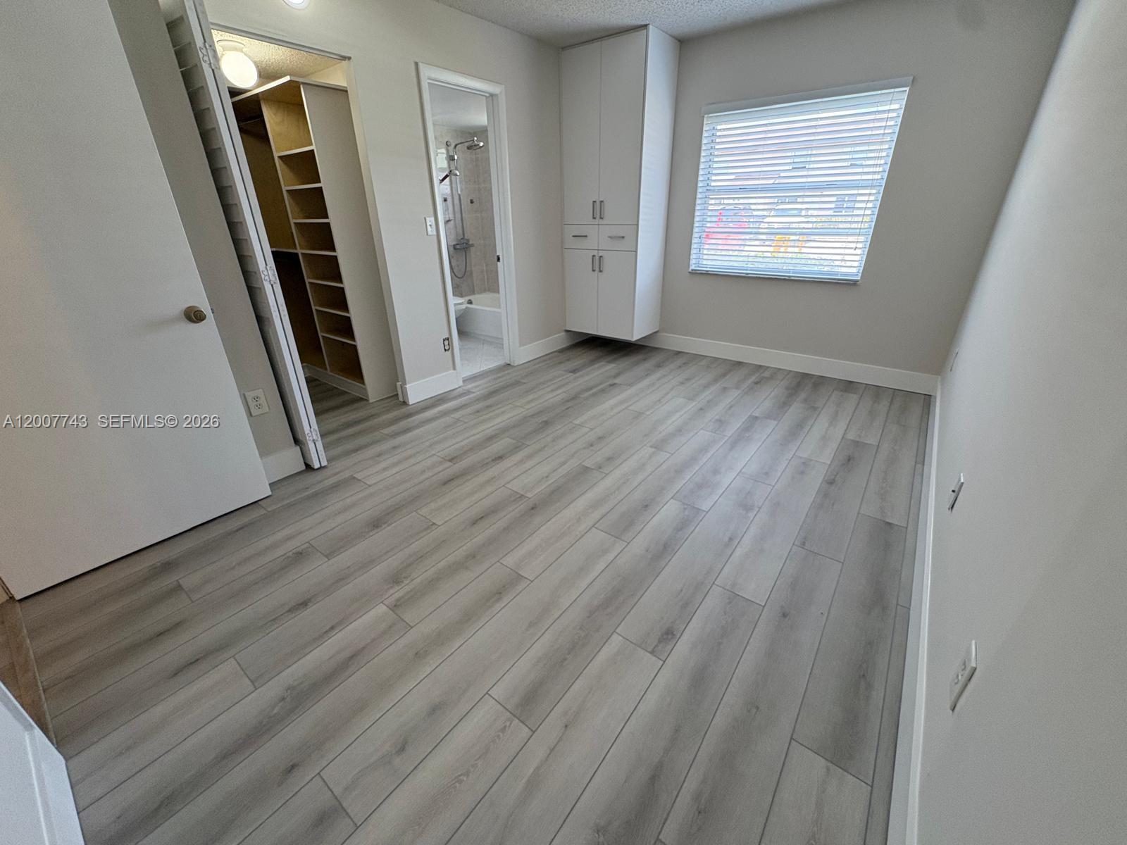 15250 Southwest 80th Street, Unit 4 Miami, FL 33193 - Photo 8 of 18 an empty room with wooden floor and windows