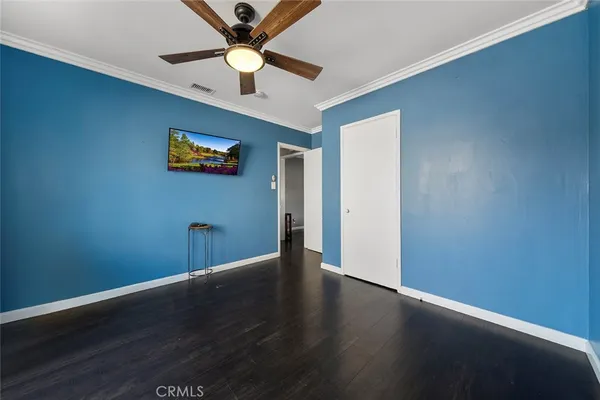 an empty room with wooden floor and a ceiling fan
