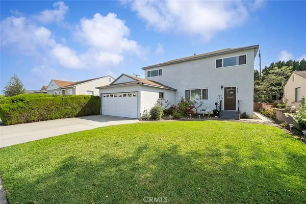 a view of a house with a big yard plants and a large tree