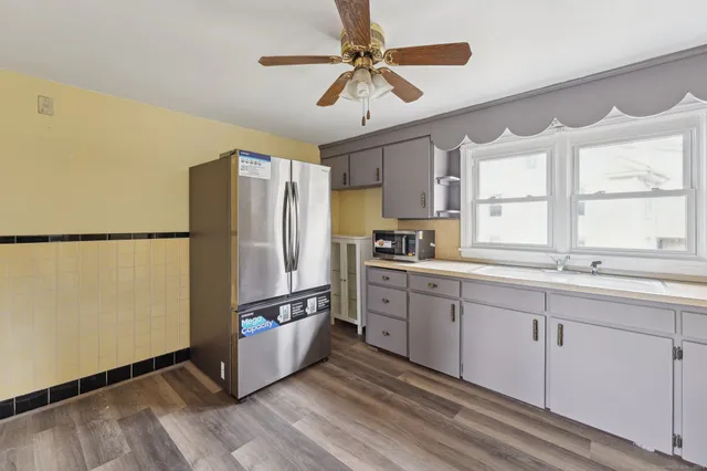 a kitchen with stainless steel appliances granite countertop a refrigerator a sink and white cabinets