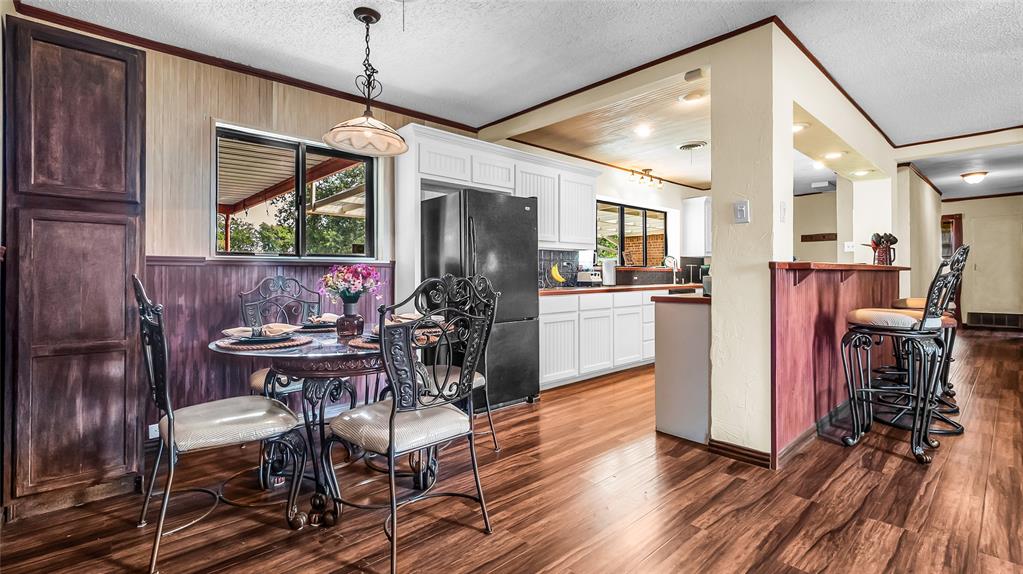 193 Eisenhower Road Denison, TX 75020 - Photo 2 of 30 Kitchen featuring healthy amount of natural light, a textured ceiling, a breakfast bar area, hanging light fixtures, and ornamental molding