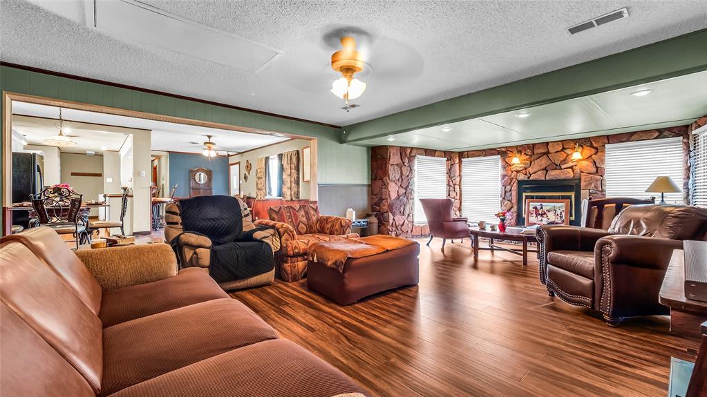 193 Eisenhower Road Denison, TX 75020 - Photo 5 of 30 Living area featuring a ceiling fan, wood finished floors, a fireplace, a textured ceiling, and wainscoting