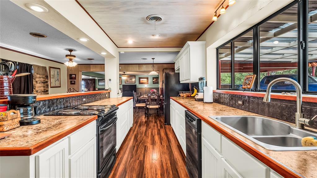 193 Eisenhower Road Denison, TX 75020 - Photo 7 of 30 Kitchen featuring white cabinets, black appliances, hanging light fixtures, dark wood-style floors, and light countertops