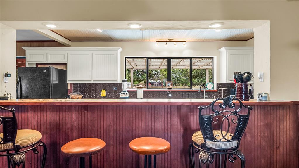193 Eisenhower Road Denison, TX 75020 - Photo 9 of 30 Kitchen with freestanding refrigerator, tasteful backsplash, a kitchen bar, wooden ceiling, and dark countertops