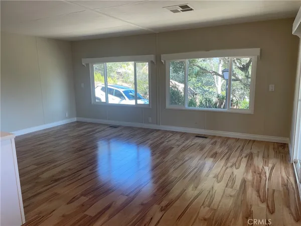 an empty room with wooden floor and windows
