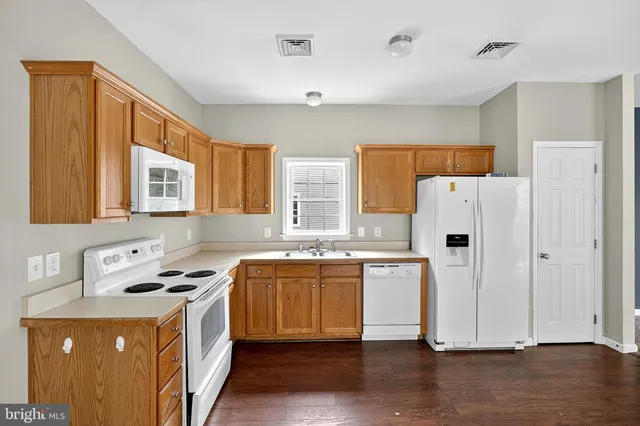 a kitchen with a refrigerator a stove a sink dishwasher and wooden cabinets