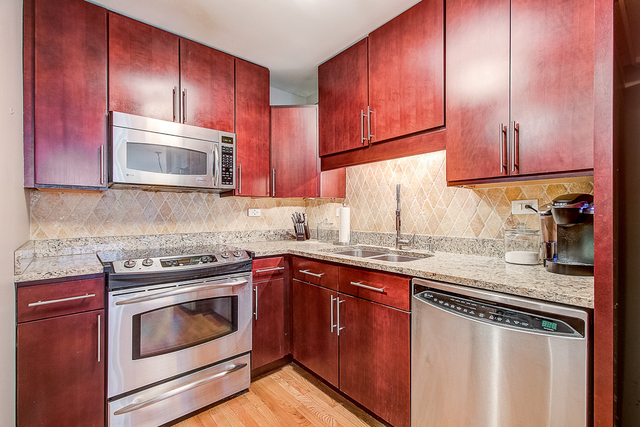 720 West Gordon Terrace, Unit 5B Chicago, IL 60613 - Photo 6 of 20 a kitchen with granite countertop wooden cabinets and stainless steel appliances