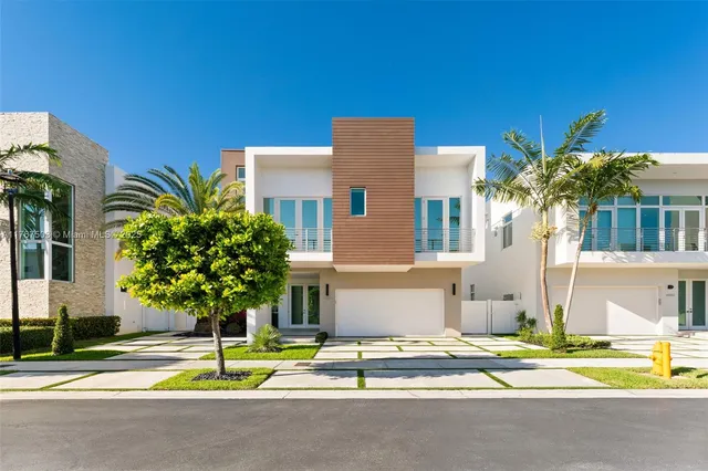 a view of a white building with a yard