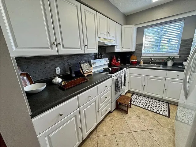 a kitchen with granite countertop white cabinets and sink