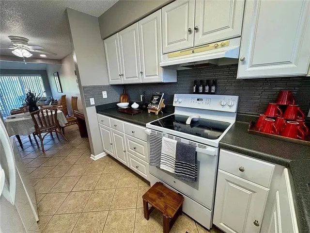 a kitchen with stainless steel appliances granite countertop a sink a stove and white cabinets