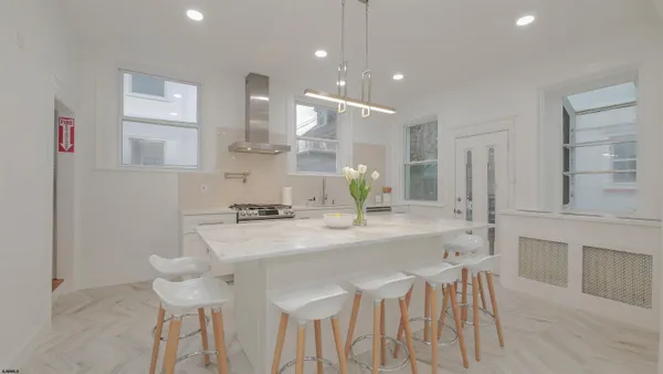 a kitchen with stainless steel appliances kitchen island granite countertop a kitchen island and chairs in it