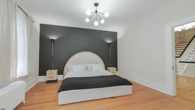 a bedroom with bed and a large mirror on the dresser
