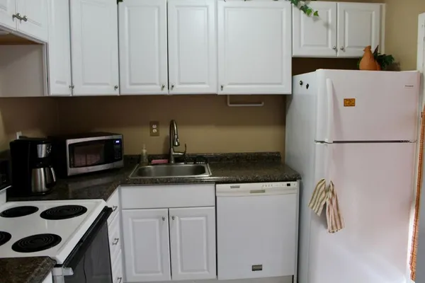 a kitchen with granite countertop a sink a stove and a refrigerator