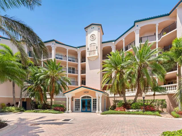 a front view of a building with palm trees