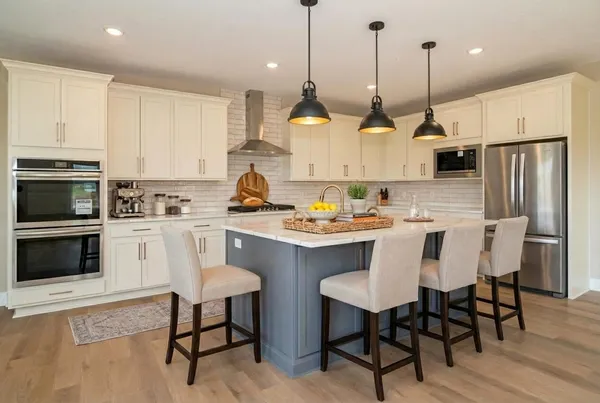 a kitchen with stainless steel appliances granite countertop a stove a kitchen island a refrigerator and a dining table with wooden floor