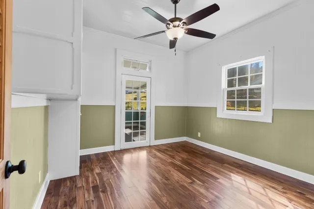 an empty room with wooden floor closet and windows