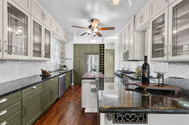 a kitchen with kitchen island granite countertop a stove dining table chairs and cabinets