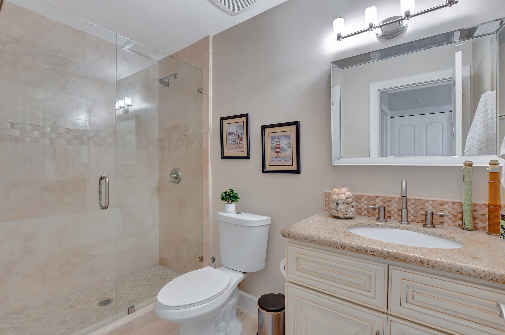 9717 Erica Court Boca Raton, FL 33496 - Photo 22 of 49 a bathroom with a granite countertop toilet a sink a mirror and shower
