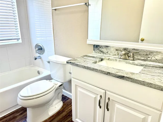a bathroom with a granite countertop toilet sink and a bathtub